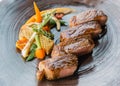 Roasted medium rare wagyu beef served with sour sauce with roasted baby vegetables on stone plate Royalty Free Stock Photo