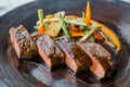 Roasted medium rare wagyu beef served with sour sauce with roasted baby vegetables on stone plate