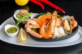 Roasted Mixed Seafood Contain Blue Crabs, Mussels, Big Shrimps, Calamari Squids with Spicy Chili Sauce and Lemon on Dish, on black Royalty Free Stock Photo