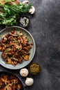 Roasted mushrooms with onion in the plate on a dark background. Top view