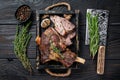 Roasted mutton lamb leg sliced in a wooden tray with meat cleaver. Black wooden background. Top view Royalty Free Stock Photo
