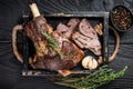 Roasted mutton lamb leg sliced in a wooden tray with meat cleaver. Black wooden background. Top view Royalty Free Stock Photo