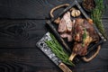 Roasted mutton lamb leg sliced in a wooden tray with meat cleaver. Black wooden background. Top view. Copy space Royalty Free Stock Photo