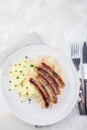 Roasted nuremberg sausages served with sour cabbage and mashed potatoes, on white plate, vertical, top view, copy space Royalty Free Stock Photo