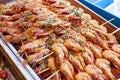 Roasted orange ready-to-eat shrimp on small wooden skewers with white and black sesame seeds and small sprigs of