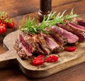 Roasted piece of beef ribeye cut into pieces on a vintage brown chopping board, rare doneness. Delicious steak Royalty Free Stock Photo