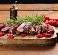 Roasted piece of beef ribeye cut into pieces on a vintage brown chopping board, rare doneness. Delicious steak, close up Royalty Free Stock Photo