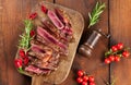 Roasted piece of beef ribeye cut into pieces on a vintage brown chopping board, rare doneness. Delicious steak, top view Royalty Free Stock Photo