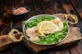 Roasted pollock or coalfish fish fillet served with green salad in a skillet. Wooden background. Top view