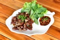 Roasted pork Chitterlings with chilli sauce spicy in a white plate on a wooden table or Grilled pork intestine.