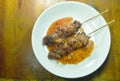 Roasted pork neck stabbing in wooden stick dressing spicy sauce on dish