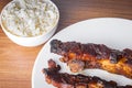 Roasted pork ribs with barbecue sauce, rice and guarana soda on a white porcelain plate. Wooden table Royalty Free Stock Photo