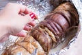 Roasted pork roll stuffed with vegetables and garlic. A woman`s hand removes threads Royalty Free Stock Photo