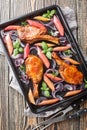 Roasted pork steaks, cutlets with bones with red onion, herbs and rhubarb close-up in a baking sheet on the table. Vertical top