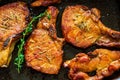 Roasted pork steaks, cutlets with bones and thyme on black baking sheet, top view