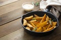 Roasted potato in a frying skillet pan on wooden table. Homemade roasted, golden potatoes slices