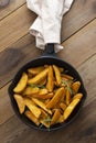 Roasted potato in a frying skillet pan on wooden table. Homemade roasted, golden potatoes slices