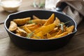 Roasted potato in a frying skillet pan on wooden table. Homemade roasted, golden potatoes slices