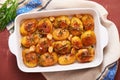 Roasted potatoes with garlic, thyme and rosemary in ceramic baking dish, top view