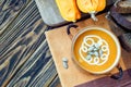 Roasted pumpkin soup with cream, fresh pumpkins and pumpkin seeds in plate on wooden background. Copy space Royalty Free Stock Photo