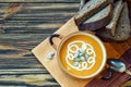 Roasted pumpkin soup with cream, fresh pumpkins and pumpkin seeds in plate on wooden background. Copy space Royalty Free Stock Photo