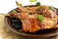 Roasted rabbit leg with prunes on a ceramic plate on light background. Close up.
