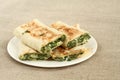 Roasted rolls of bread lavash filled with herbs and feta cheese at white plate on rough linen cloth Royalty Free Stock Photo