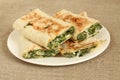 Roasted rolls of bread lavash filled with herbs and feta cheese at white plate on rough linen cloth Royalty Free Stock Photo
