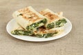 Roasted rolls of bread lavash filled with herbs and feta cheese at white plate on rough linen cloth Royalty Free Stock Photo