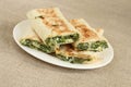 Roasted rolls of bread lavash filled with herbs and feta cheese at white plate on rough linen cloth. Closeup Royalty Free Stock Photo