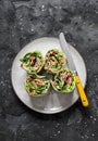 Roasted salmon, avocado puree, green salad tortilla wrapped roll sandwich on a dark background, top view