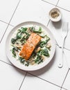 Roasted salmon with creamy spinach mushrooms sauce on a light background, top view. Salmon florentine