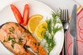 Roasted salmon, lemon and tomatoes on the white plate.