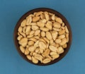 Roasted salted peanuts in bowl on blue background, top view Royalty Free Stock Photo