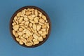 Roasted salted peanuts in bowl on blue background, top view Royalty Free Stock Photo