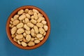 Roasted salted peanuts in bowl on blue background, top view Royalty Free Stock Photo