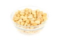 Roasted and salted peanuts in glass bowl over white