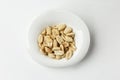 Roasted salted peanuts in a white plate. Appetizing snack. Close-up. White background