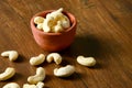 Roasted salted raw cashew nuts in wooden bowl on rustic table, healthy vegetarian snack, Anacardium occidentale, Cashews on white