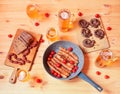 Roasted sausages, beer mugs, beer glasses, bread and little chorizo sausages on wooden table. Top view Royalty Free Stock Photo