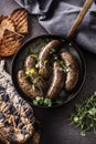 Roasted sausages in pan with bread and herbs. Royalty Free Stock Photo