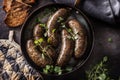 Roasted sausages in pan with bread and herbs. Royalty Free Stock Photo