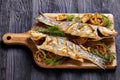 Roasted sea bass on a black wooden table, close-up