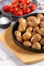 Roasted small whole potatoes in a cast iron skillet on concrete background. Vegetarian or vegan food concept