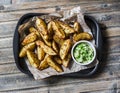 Roasted spices potato with avocado salsa on wooden background, top view. Delicious snack or appetizers.