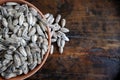 Sunflower seeds in a terracotta bowl on old weathered dark wood