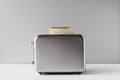 Roasted toast bread popping up of stainless steel retro toaster for breakfast preparation on a gray background. Royalty Free Stock Photo