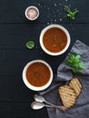 Roasted tomato soup with fresh basil, spices and bread in rustic metal bowls over black background Royalty Free Stock Photo