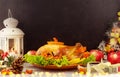 Roasted traditional Turkey with berries and apples on wooden table background with black backdrop.