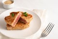 Roasted tuna steak in sesame seeds with parsley garnish on a plate on a white table Royalty Free Stock Photo